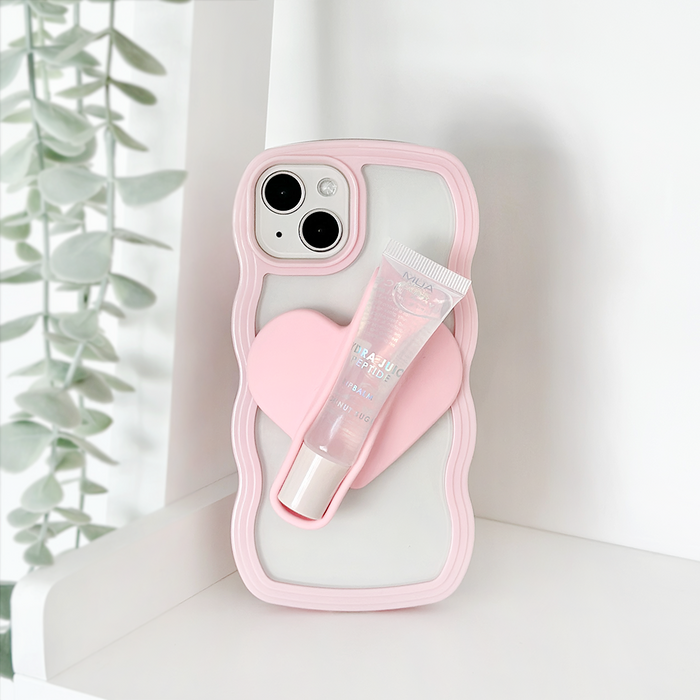 Pink Coconut Lane lip gloss holder sticker with a heart grip on a white shelf next to green plants.