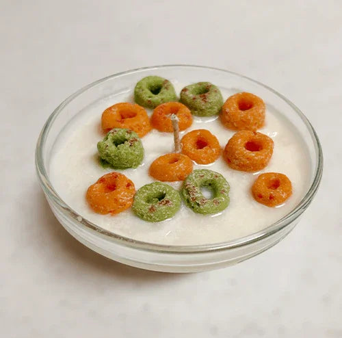 Scented candle in a bowl, designed to look like milk with colorful cereal pieces on top.
