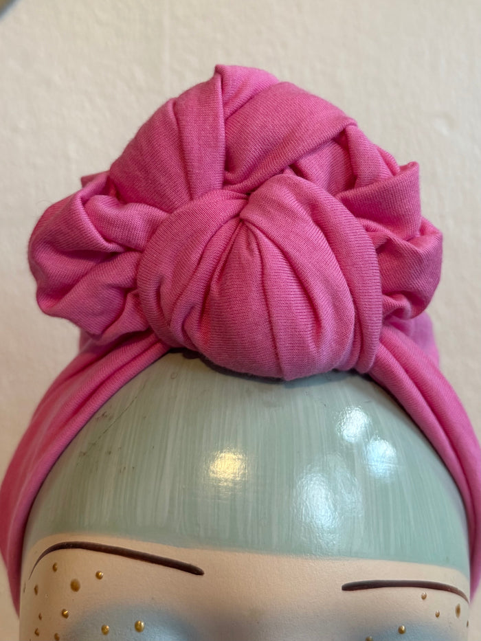 Pink knotted headband  with a plain background