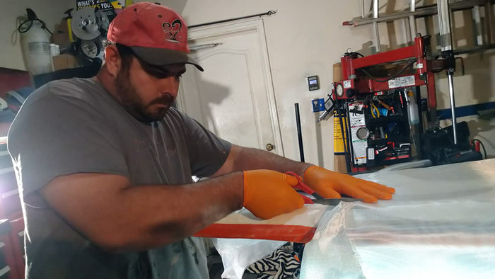 Cutting six ounce fiberglass cloth fabric with scissors for surfboard.