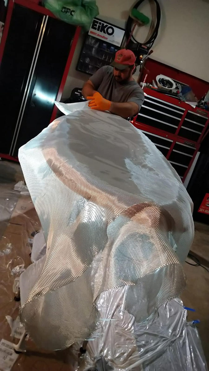 Measuring out fiberglass cloth and laying it on top of surfboard. Cutting fiberglass to size.