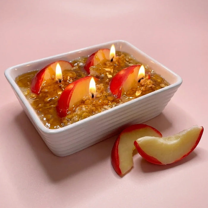 Apple crumble dessert candle with realistic apple slices and lit wicks in a white dish