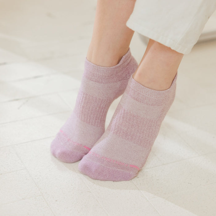 Ankle compression socks in a pink marl pattern, worn on feet against a light floor.