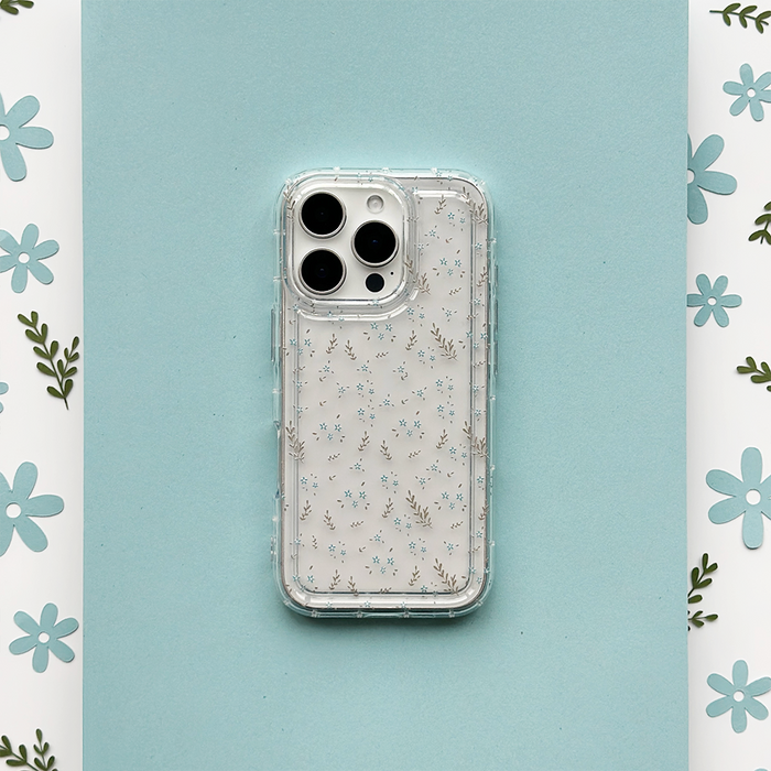 Clear phone case with blue floral pattern by Coconut Lane, shown on a blue background beside white floral paper.