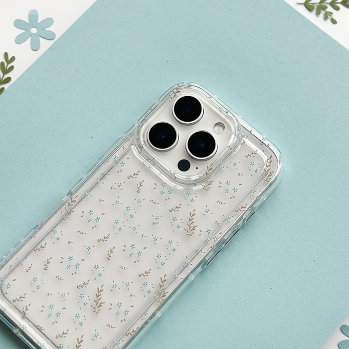 Clear Coconut Lane Blooming Blues phone case with blue floral pattern on a light blue surface, floral cutouts beside it.