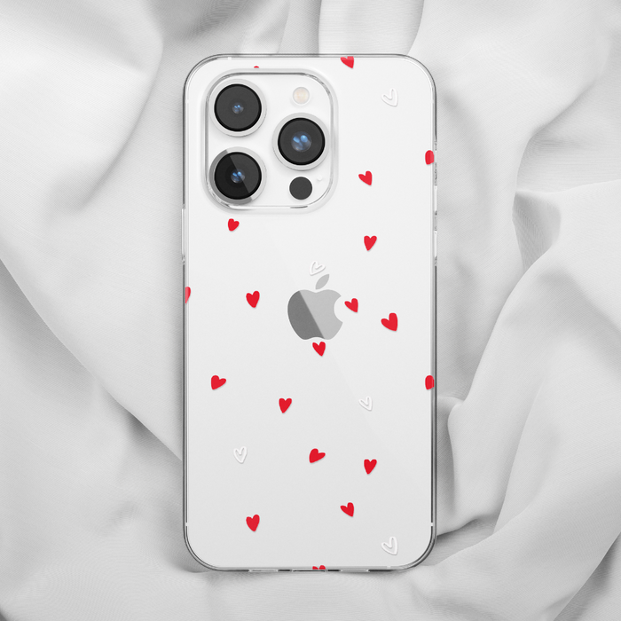 Clear iPhone 15 case with red and white heart pattern, displayed on soft white fabric.