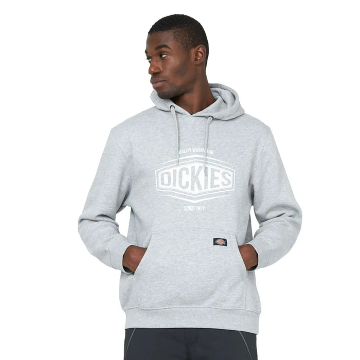 A man wearing a gray hoodie with the brand name Dickies displayed prominently stands with his hands in the pockets gazing slightly to the side against a plain background.