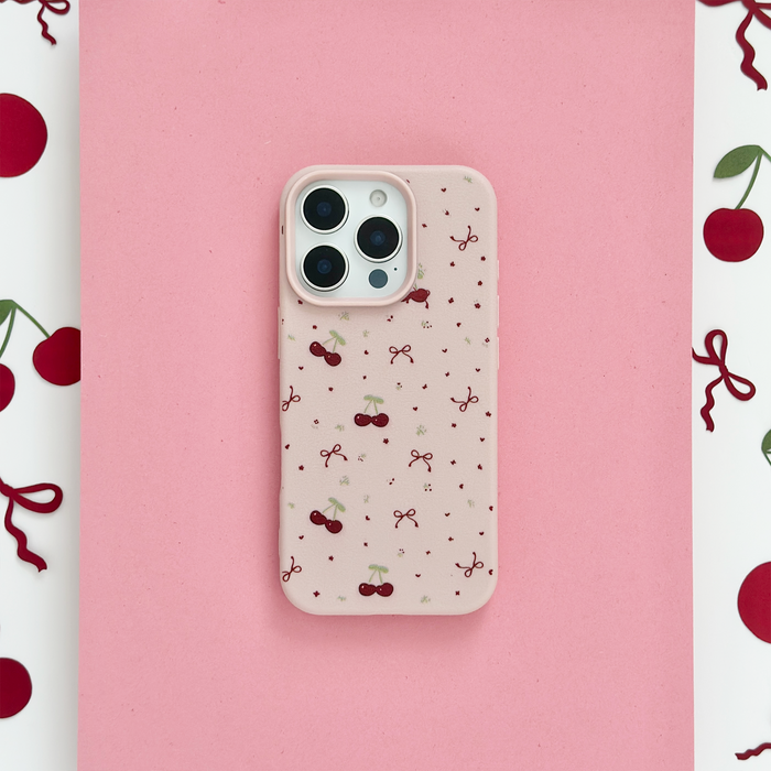 Pink phone case with a pattern of small red cherries and bows.