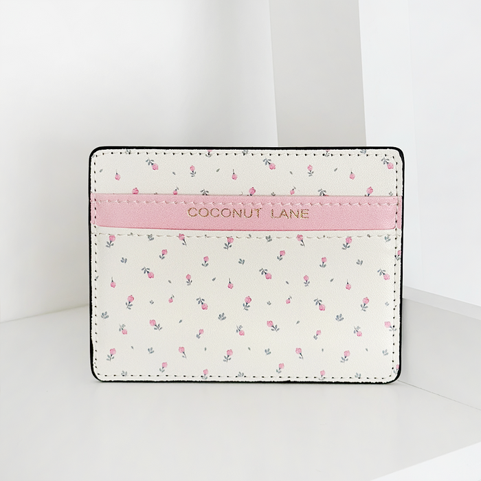 White vegan leather card holder with pink floral pattern, stripe detail, and gold Coconut Lane logo.