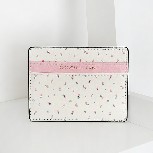 White vegan leather card holder with pink floral pattern, stripe detail, and gold Coconut Lane logo.