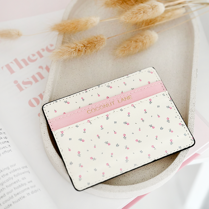 White card holder with a ditsy floral pattern on a tray beside dried flowers and an open magazine.