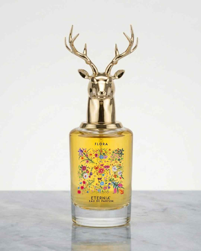Floral perfume bottle with gold deer antler cap and yellow glass, floral label on front