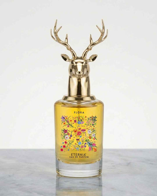 Floral perfume bottle with gold deer antler cap and yellow glass, floral label on front