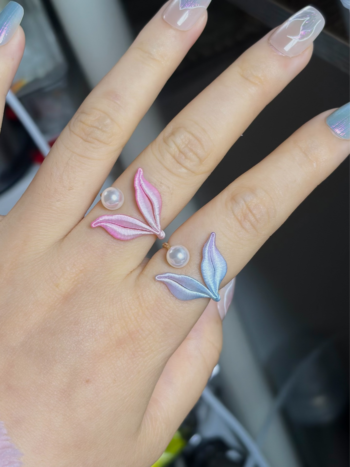 A hand wearing a blue mermaid tail ring and holding a blue mermaid tail necklace-6