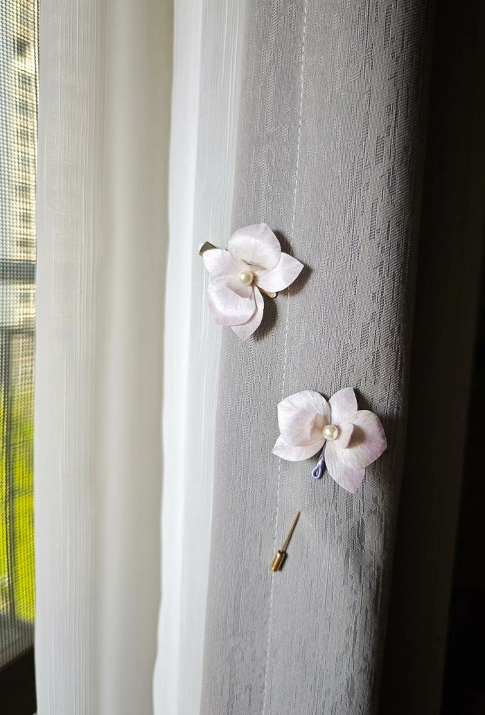 Two handmade Ronghua floral hair accessories with a butterfly - orchid design attached to a curtain