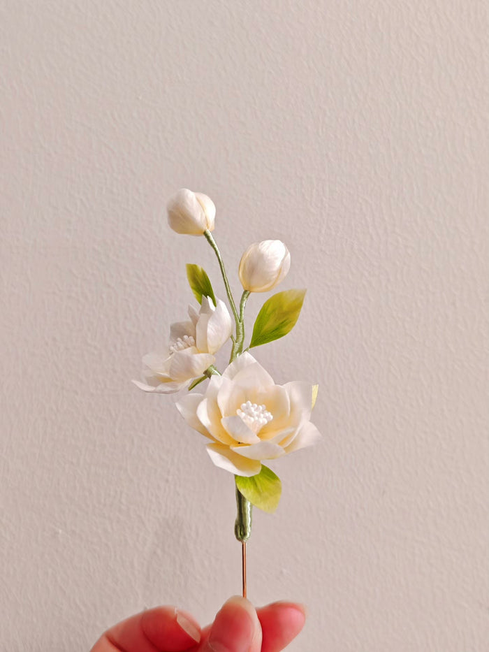 Handmade Ronghua jasmine flower hair accessory with open and bud - shaped flowers and green leaves