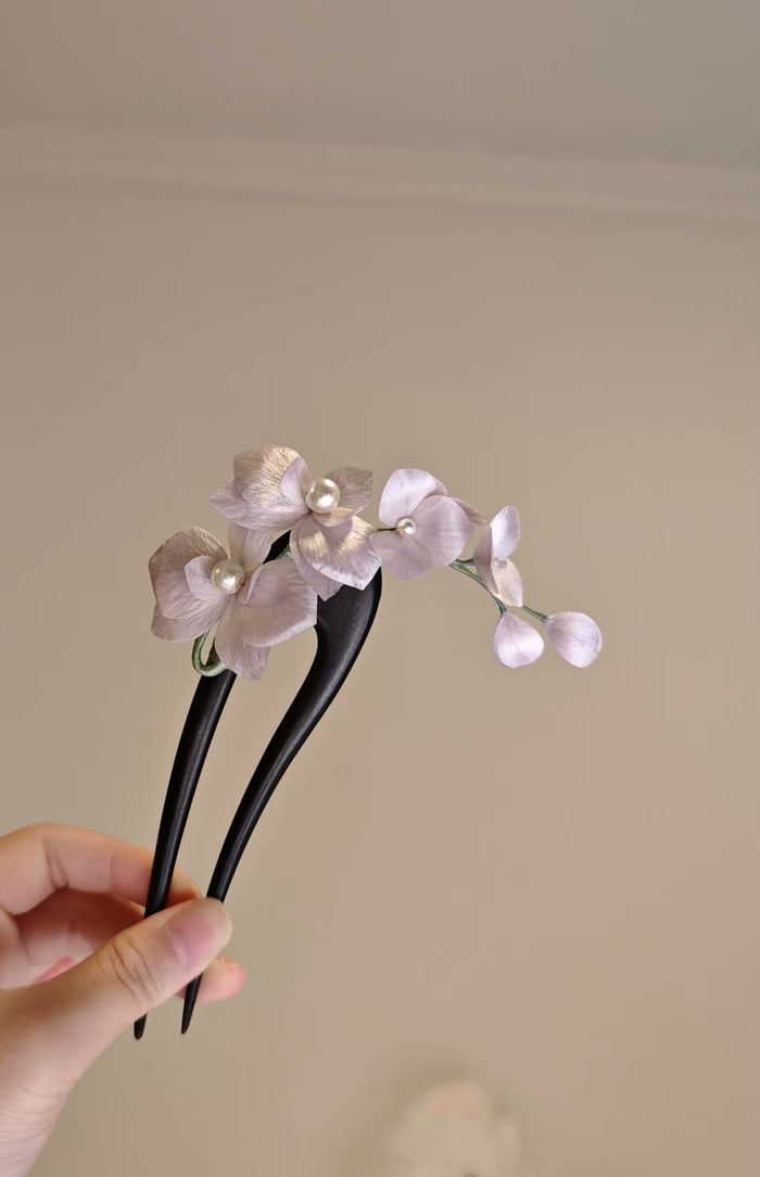 Handmade Ronghua orchid hair accessory with silk flowers and pearls held in a hand
