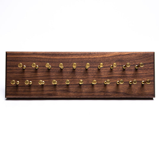A KirbyAllison.com Hanger Project Small Tie Rack - Walnut/Brass Pegs with a capacity for holding numerous ties, featuring brass pins on it.