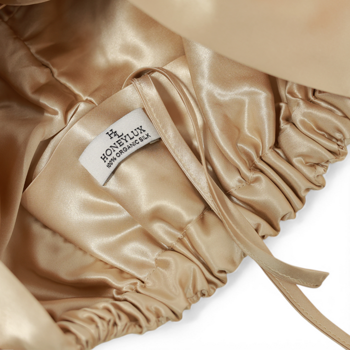 Champagne silk hair bonnet with 'HONEYLUX' 100% Oraganic Silk label on a light background