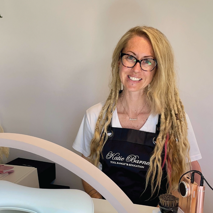 Woman with long blonde hair wearing glasses and a black apron with Katie Barnes Tool Range logo