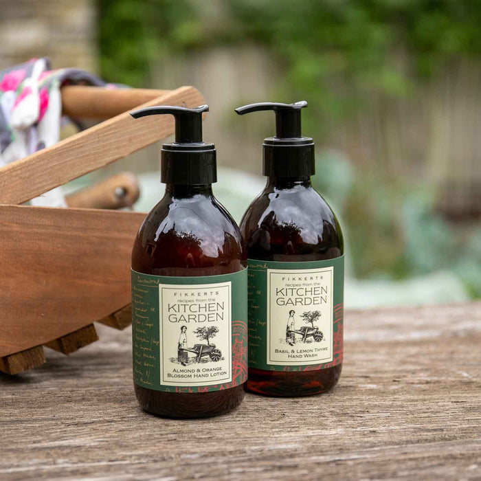 Two pump bottles of hand wash and lotion with 'Kitchen Garden' label, placed on a wooden surface with a blurred background.