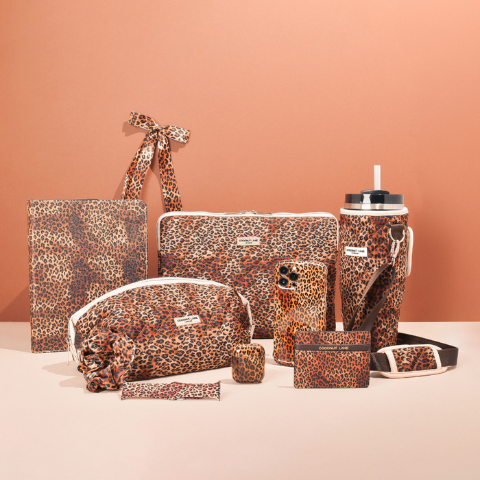 Leopard print card holder with gold accents by Coconut Lane on a peach background.
