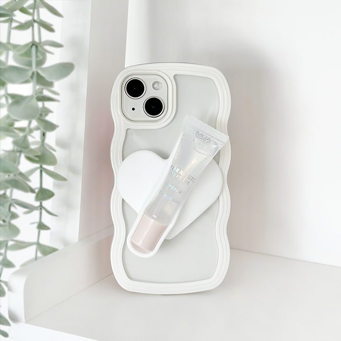 White Coconut Lane lip gloss holder sticker on a wavy phone case with heart grip, next to green leafy plant.