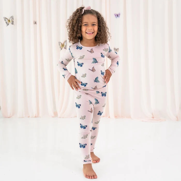 Girl wearing Kyte Baby Blush Butterfly long sleeve pajamas in soft bamboo rayon fabric.