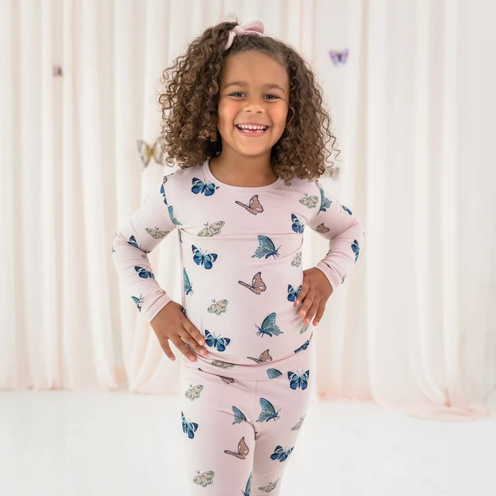 Child wearing Kyte Baby Blush Butterfly pajamas showing breathable long sleeve top and matching pants.