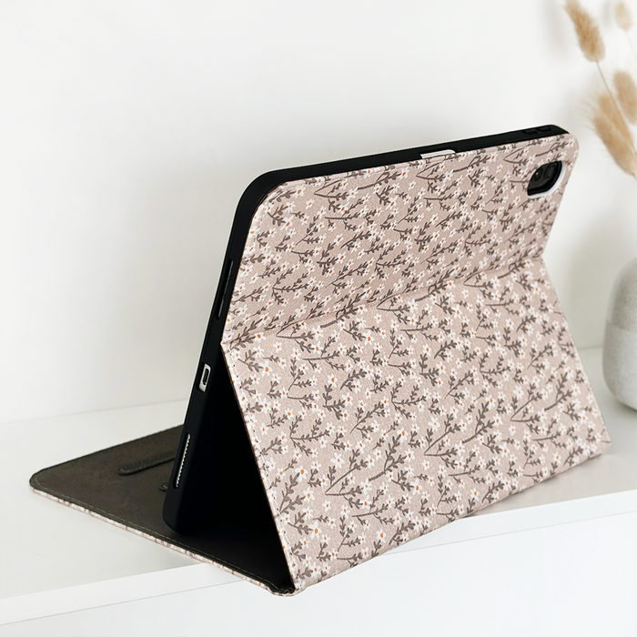Nude Flowers iPad case by Coconut Lane holding an open tablet on a white surface with dried grass in the background.
