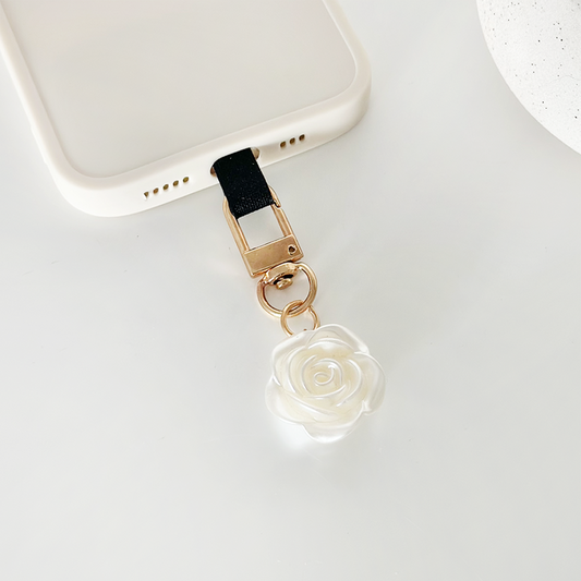 White phone case with black strap, gold clasp, and a white rose charm from Coconut Lanes Pearl Flower Keyring Bundle.