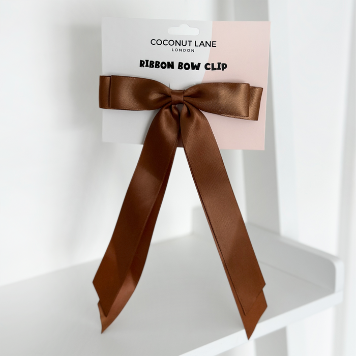 Brown ribbon bow hair clip on a white Coconut Lane card.