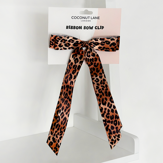 Leopard print ribbon bow clip on Coconut Lane branded packaging, placed on a white shelf.