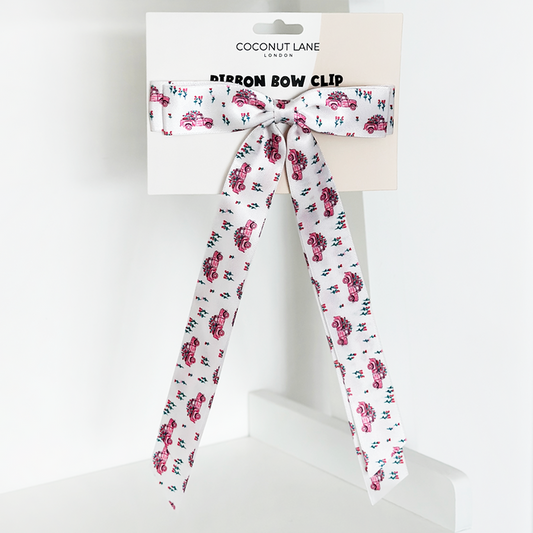 Pink ribbon bow hair clip with a red truck pattern, displayed on Coconut Lane branded packaging.
