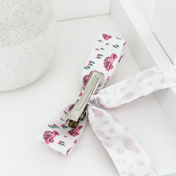 Coconut Lane ribbon bow clip featuring a pink car and floral print, displayed on a white surface.