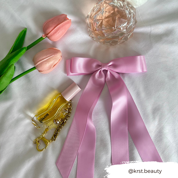 Peony pink ribbon bow hair clip by Coconut Lane beside a keychain and tulips on a white background.