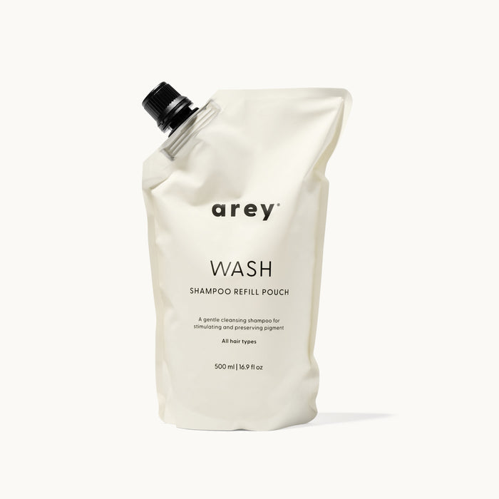 Arey Wash Shampoo Refill Pouch on a cream background. Label reads: arey. WASH. SHAMPOO REFILL POUCH. A gentle cleansing shampoo for stimulating and preserving pigment. All hair types. 500 ml / 16.9 fl oz.