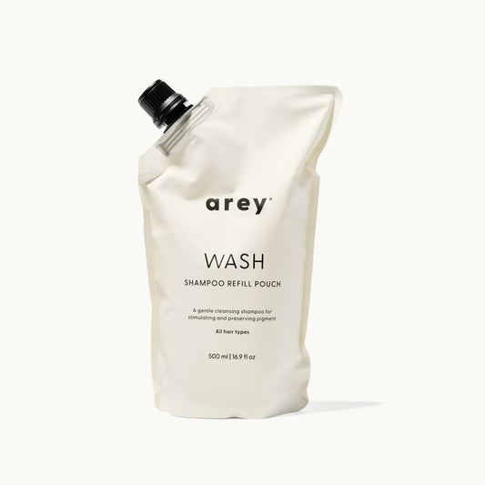 Arey Wash Shampoo Refill Pouch on a cream background. Label reads: arey. WASH. SHAMPOO REFILL POUCH. A gentle cleansing shampoo for stimulating and preserving pigment. All hair types. 500 ml / 16.9 fl oz.