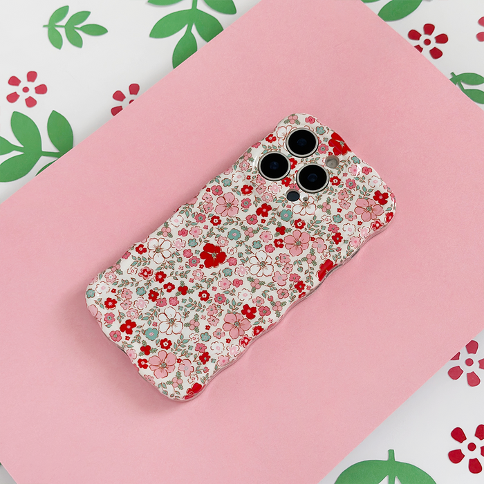 Coconut Lane wavy phone case with cute floral pattern, shown on a pink surface and colorful floral background.
