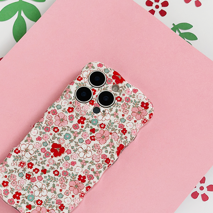 Wavy phone case with cute flower pattern on a pink background, displayed on a matching floral sheet.