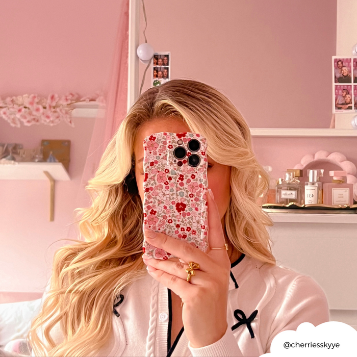 Blonde woman in a pink room holds a wavy phone case with cute flower pattern for mirror selfie.