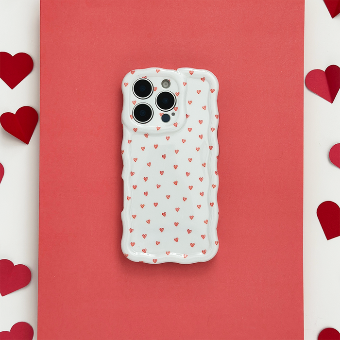 Wavy phone case with mini heart pattern on a red background, surrounded by paper hearts.
