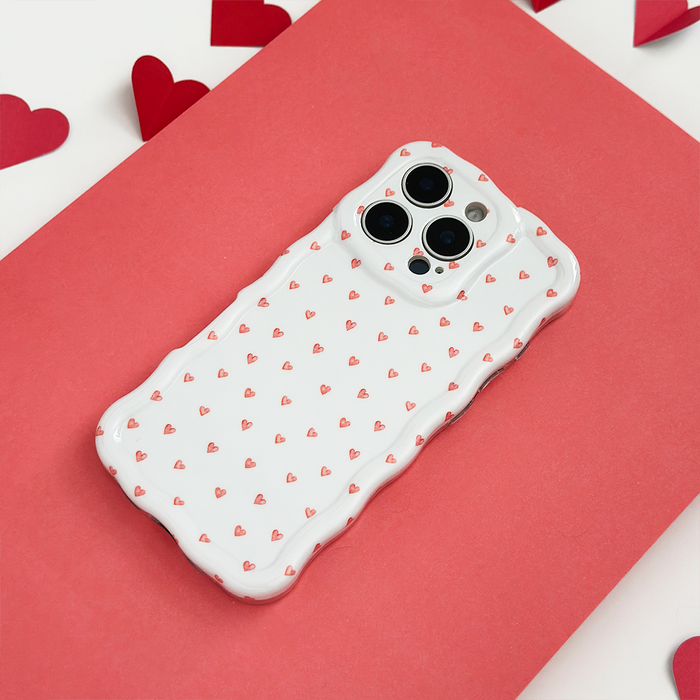 Wavy phone case with mini heart pattern on a red background, surrounded by scattered paper hearts.