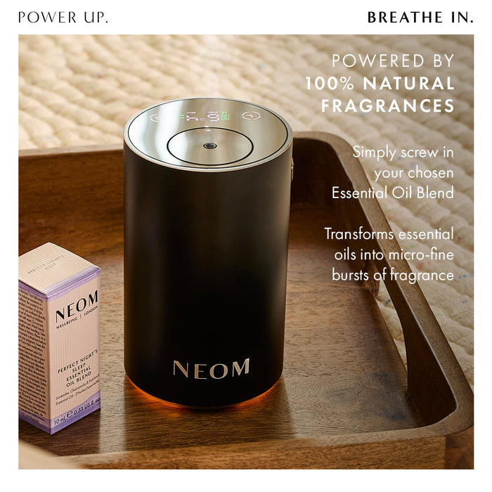 “Power Up. Breathe In"  NEOM diffuser on a bedside tray with essential oil bottle. Text reads: Powered by 100% natural fragrances. Simply screw in your chosen essential oil blend. Transforms essential oils into micro-fine bursts of fragrance.”