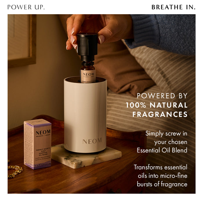 “Power Up. Breathe In"  NEOM diffuser on a bedside tray with essential oil bottle. Text reads: Powered by 100% natural fragrances. Simply screw in your chosen essential oil blend. Transforms essential oils into micro-fine bursts of fragrance.”